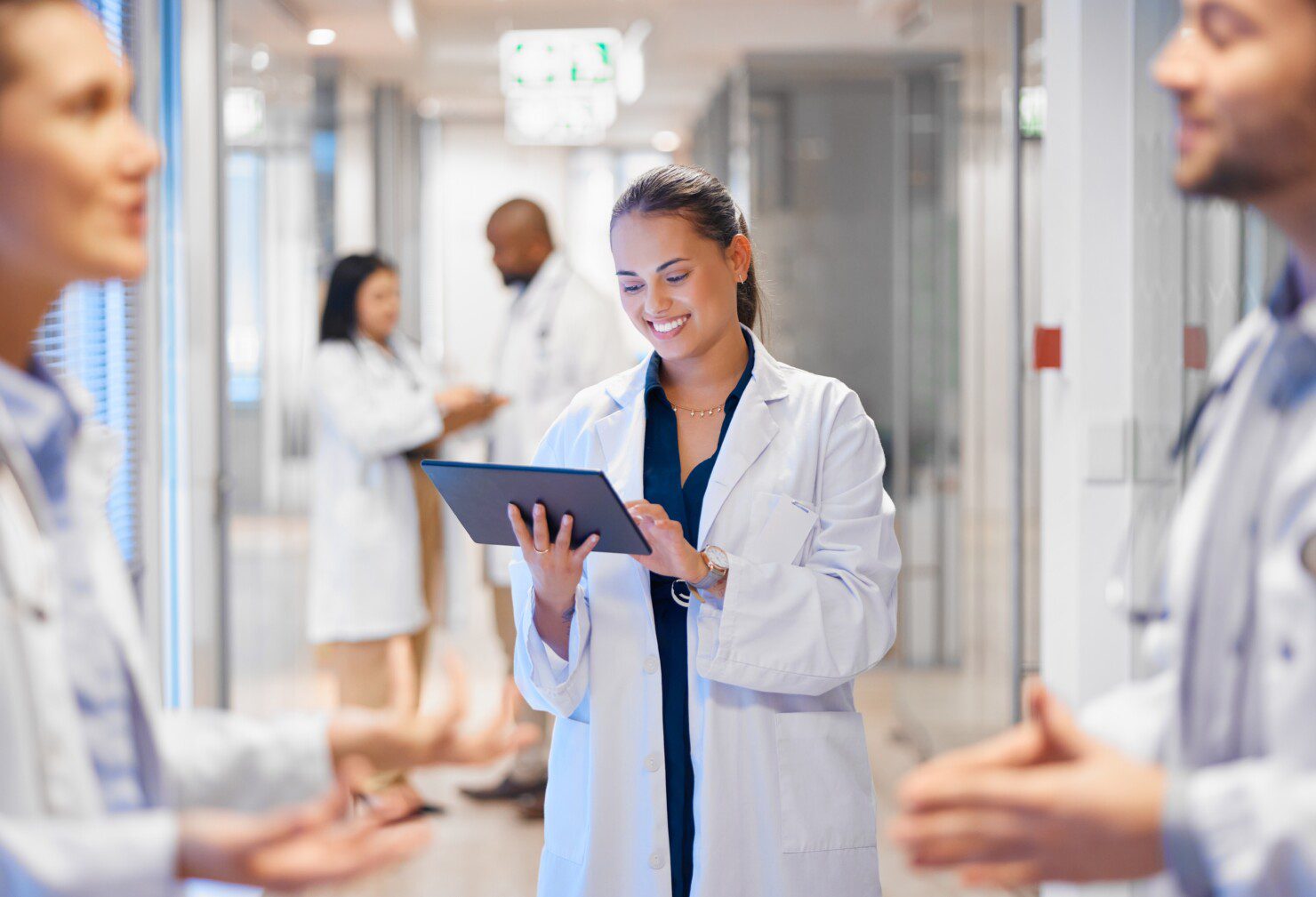 Female Doctor with brown hair, holding a tablet device and smiling